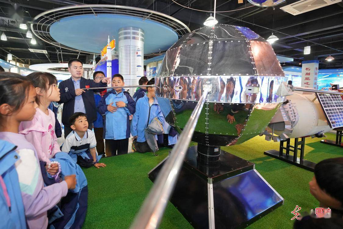 2023年5月13日,山东烟台,学生们在观看"东方红一号"卫星模型.