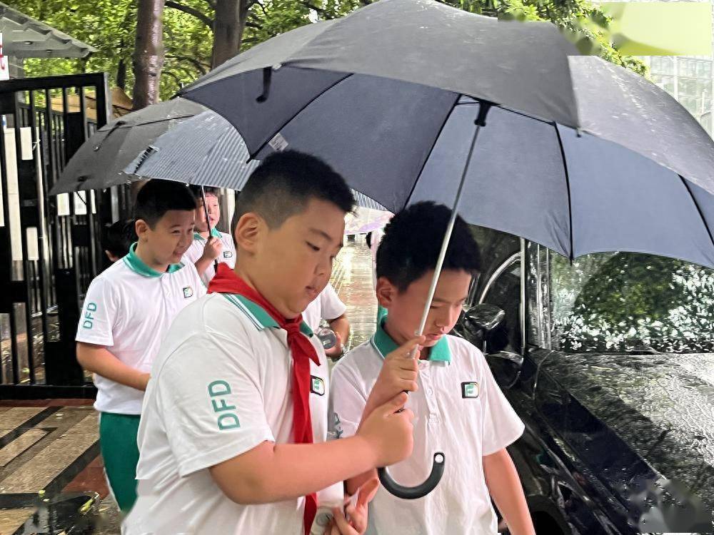 雨鞋广州市第十八中学学生跑步冲进学校家长在风雨中送孩子上学撑伞