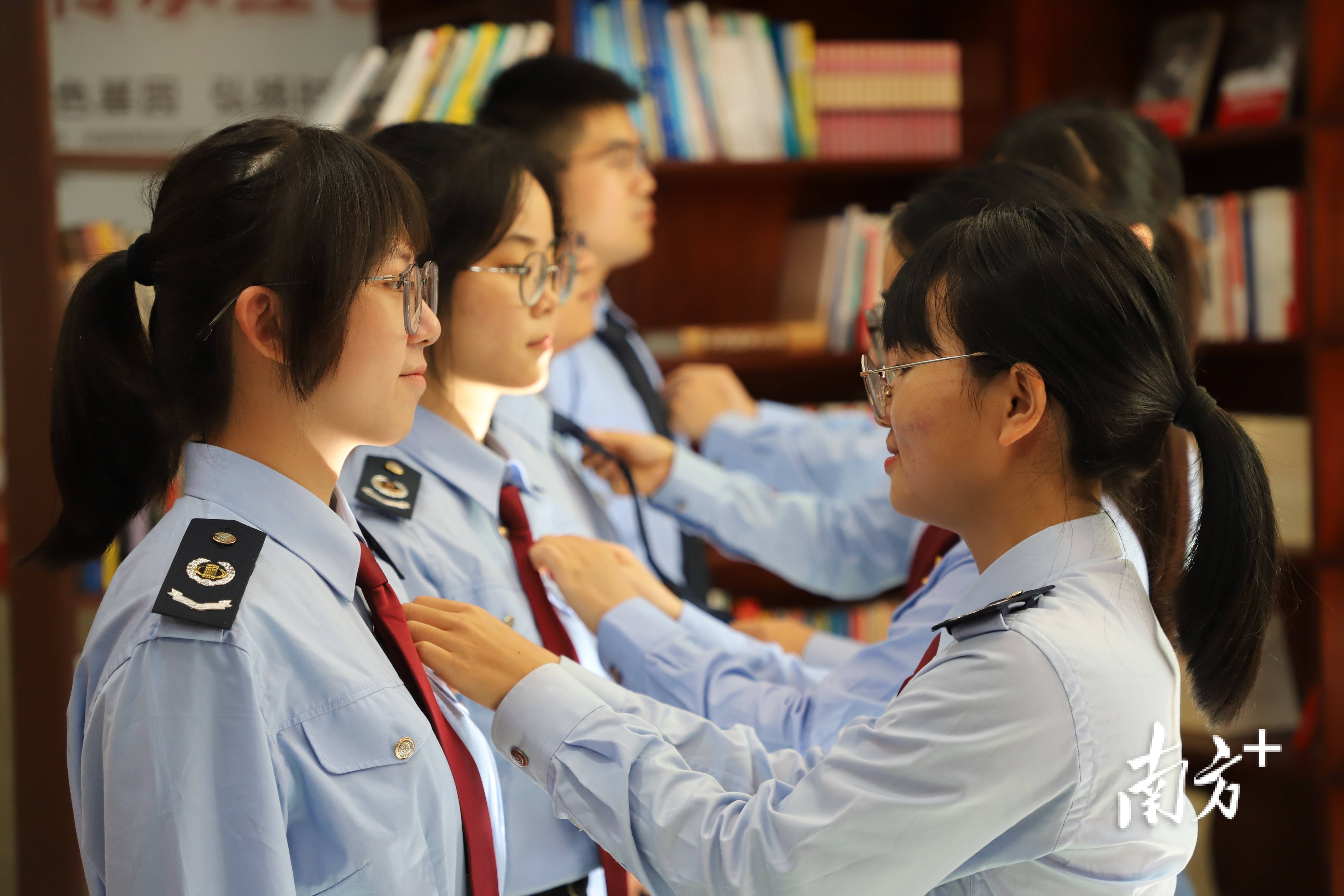 在税服税徽发放佩戴仪式上,税务人员为2023年新录用公务员整理着装.